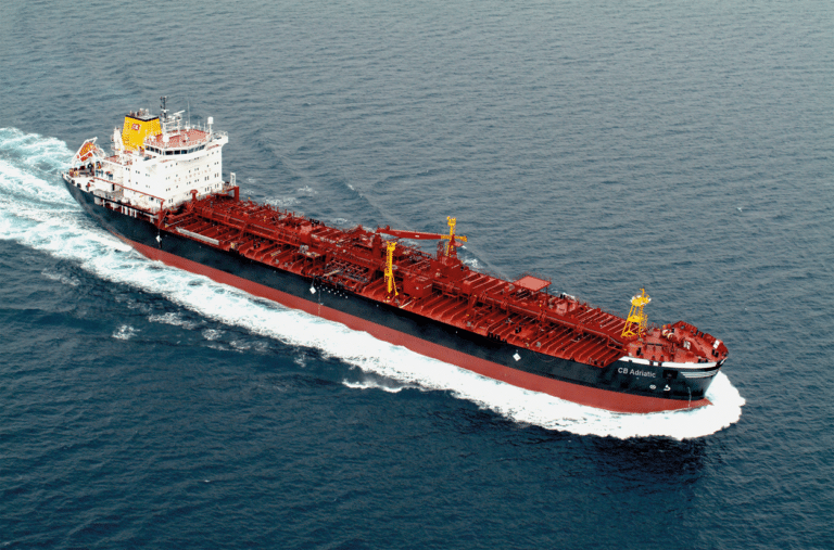An overview of a red and black tanker vessel sailing diagonally through the photo