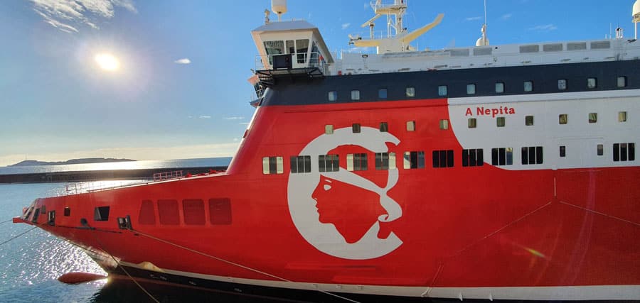 A close-up side view of the bow of a red passenger ship with white details
