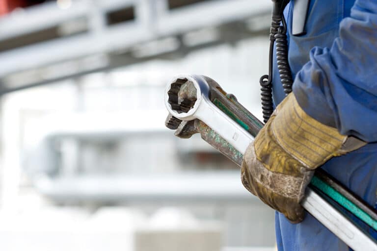 A close-up of a maintenance worker's hands gripping tools for predictive maintenance