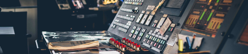 A close-up of the controls at the bridge of a maritime vessel, with a manual laid open in front