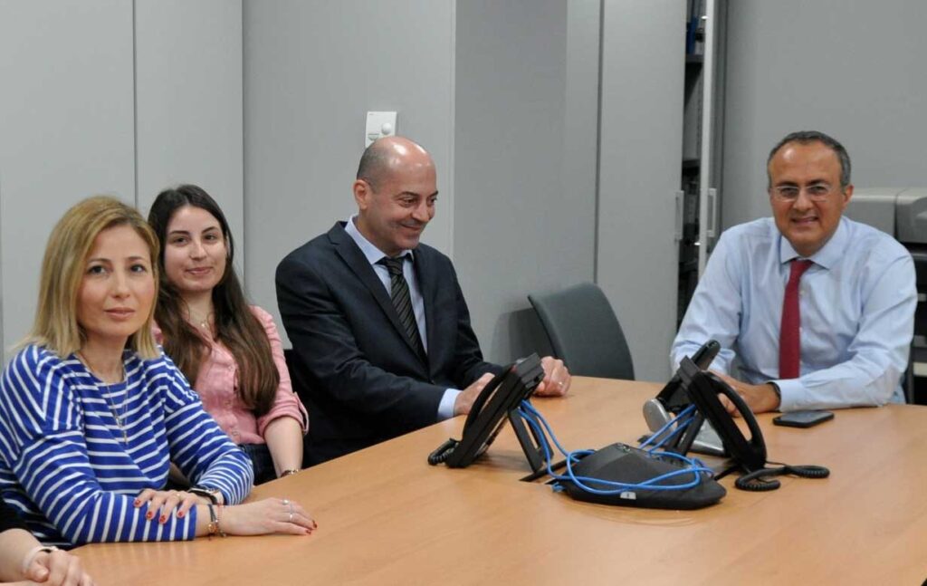 A picture of Attica employees smiling at the camera while sitting at a conference table