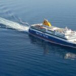 A wide shot of a passenger ship cutting through the sea at great speed