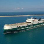 A wide shot from the side of a Grimaldi Hybrid RoRo vessel gliding across a calm sea