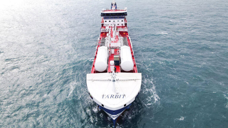 A bird's-eye view of the TARBIT maritime vessel navigating the open sea, with the perspective coming from the front of the ship