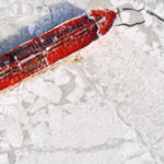 An overview of a maritime icebreaker vessel cutting through thick ice, creating a path as it powers through the frozen waters