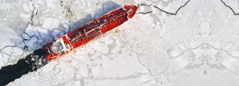 An overview of a maritime icebreaker vessel cutting through thick ice, creating a path as it powers through the frozen waters