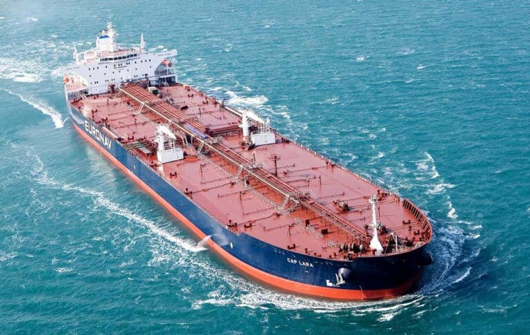 An oil tanker navigates through the vast ocean, showcasing its massive structure against the blue waters