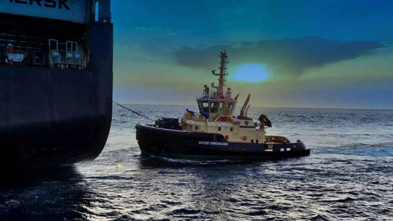 A close-up of a SVITZER tugboat maneuvering alongside a large MAERSK maritime vessel