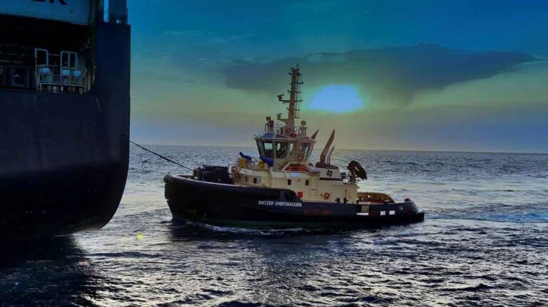 A close-up of a SVITZER tugboat maneuvering alongside a large MAERSK maritime vessel